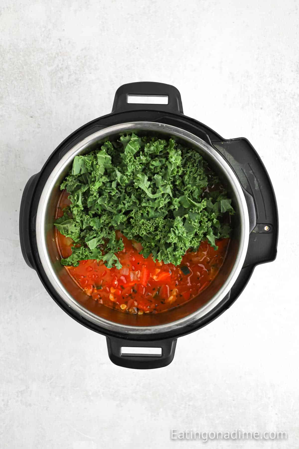 Kale has been added to the cook soup mixture in the instant pot.