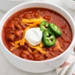 A bowl of pumpkin chili topped with sour cream, jalapenos, and shredded cheese.