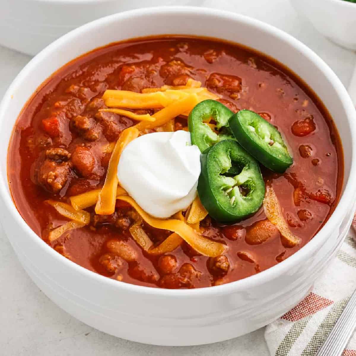 A bowl of pumpkin chili topped with sour cream, jalapenos, and shredded cheese.