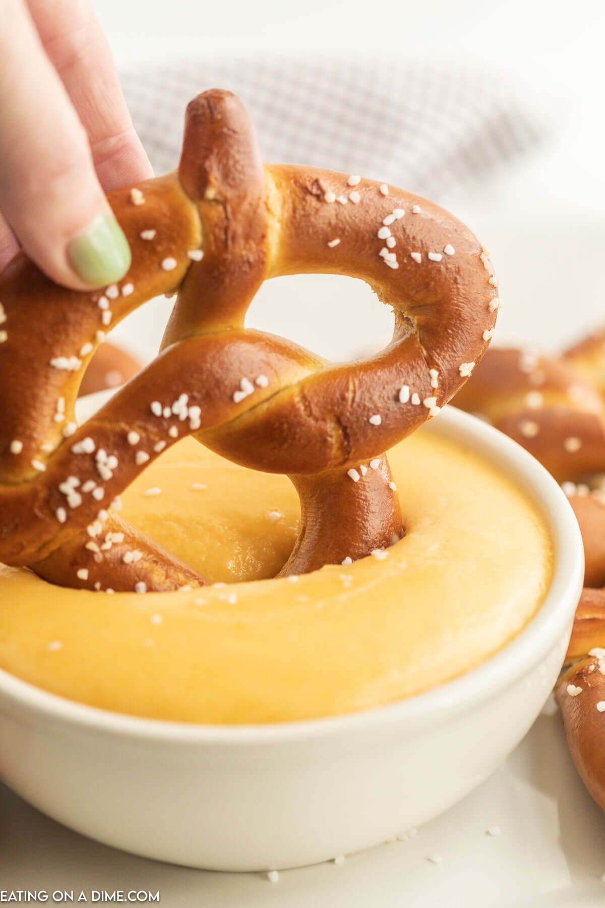 Dipping pretzels in a bowl of cheese dip