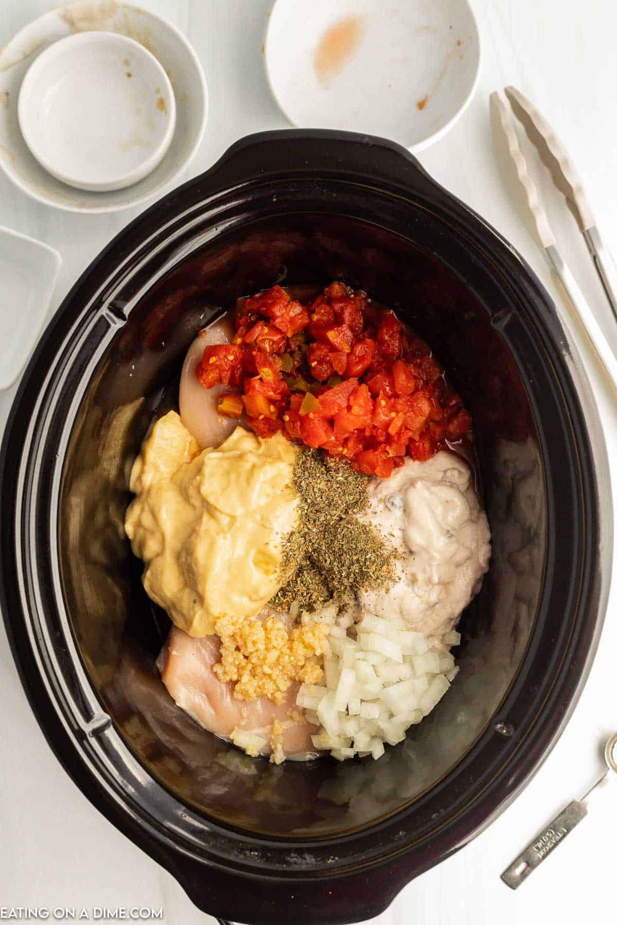 Chicken topped with diced tomatoes, cream of chicken soup and mushroom soup, onion, garlic and italian seasoning in the slow cooker
