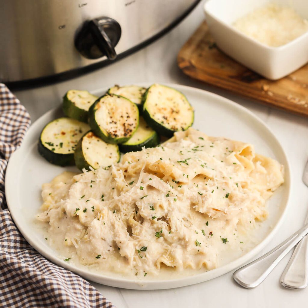 Chicken Alfredo Lasagna on a plate with a side of zucchini 