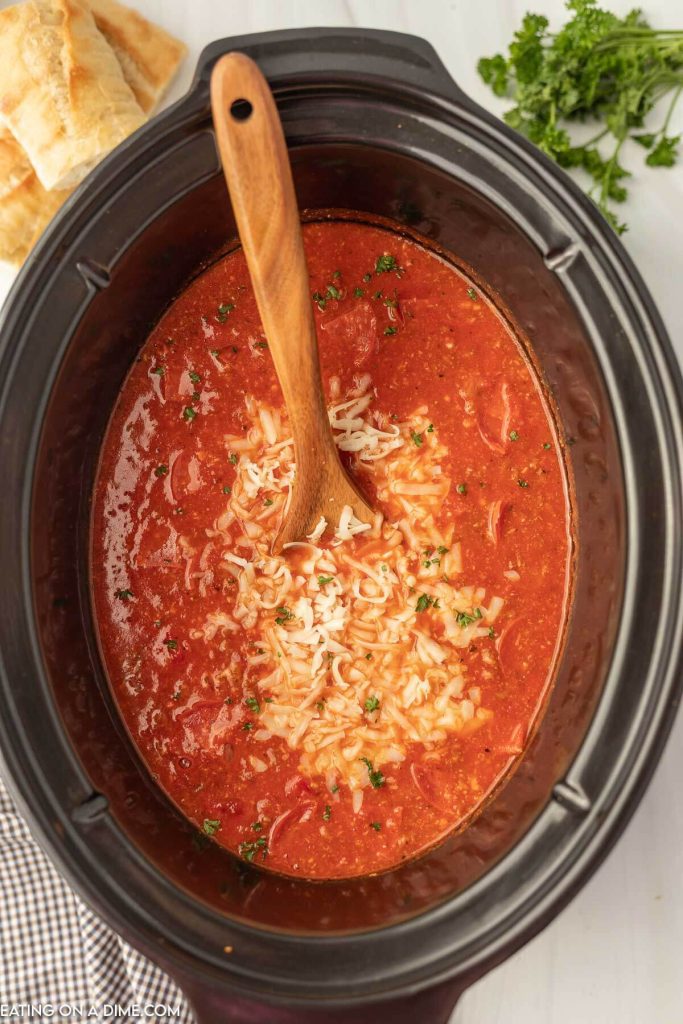 Pizza Soup in the crock pot with a wooden spoon