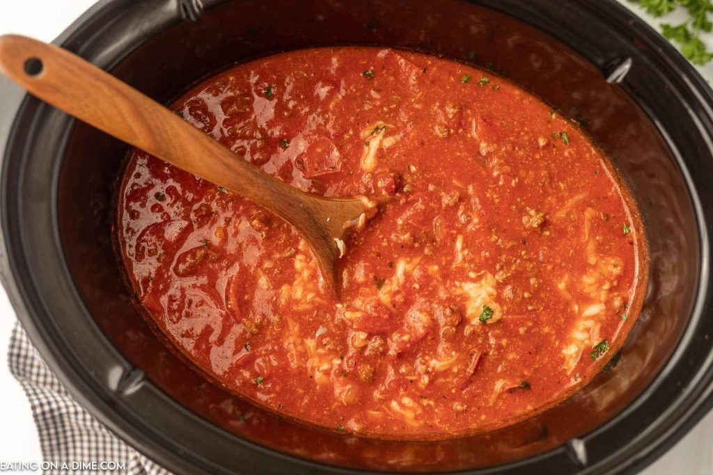 Pizza soup in the crock pot with a wooden spoon