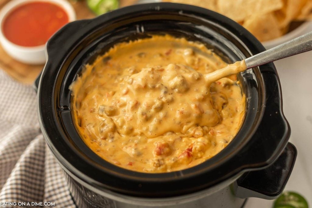 Sausage Cheese Dip in the Slow Cooker being stirred by a spoon
