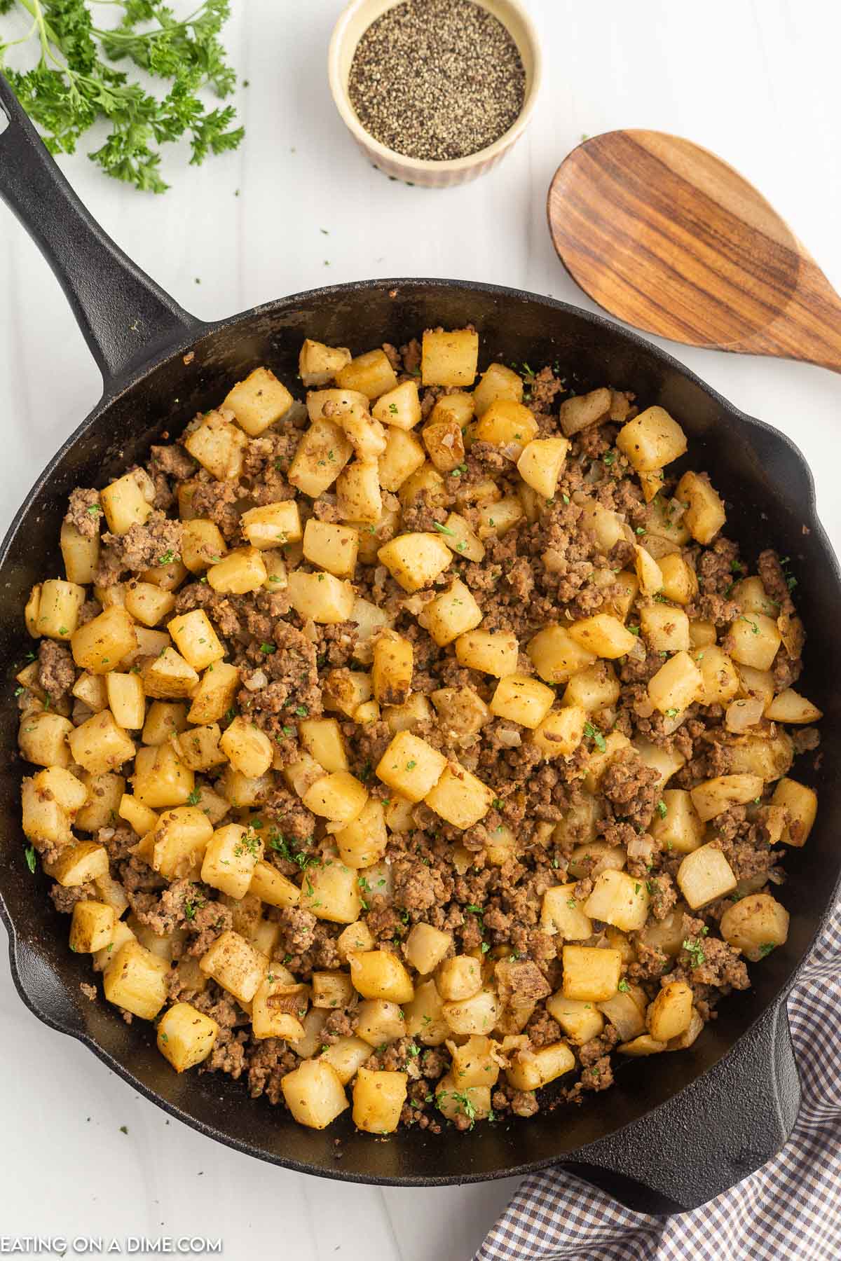 Hamburger hash in a skillet with a wooden spoon