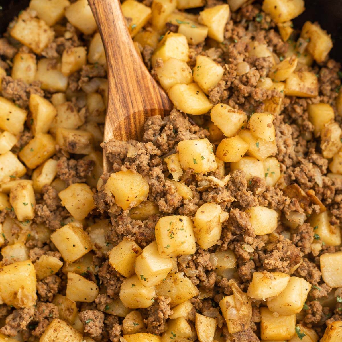 Hamburger hash in a skillet with a wooden spoon