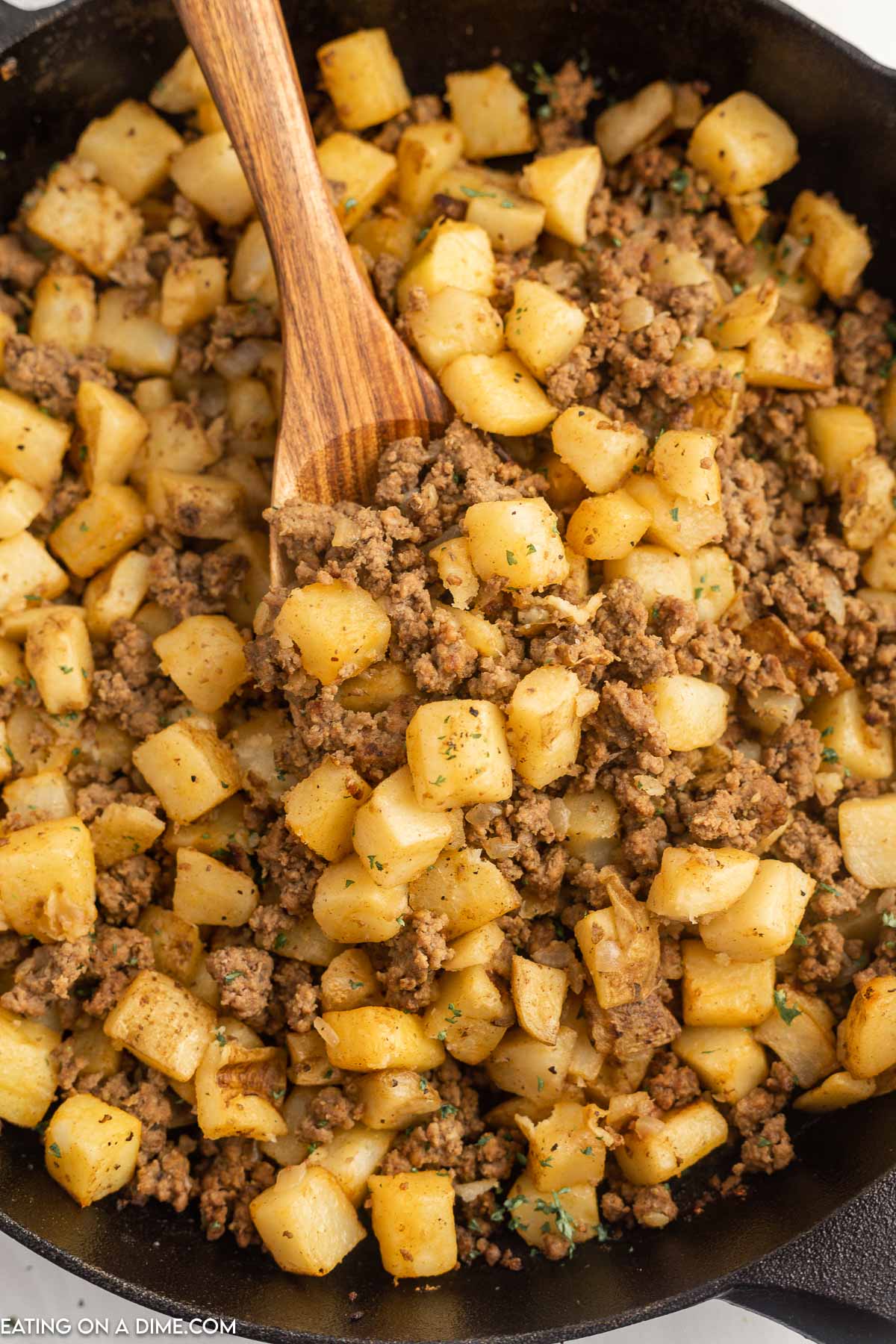 Hamburger hash in a skillet with a wooden spoon