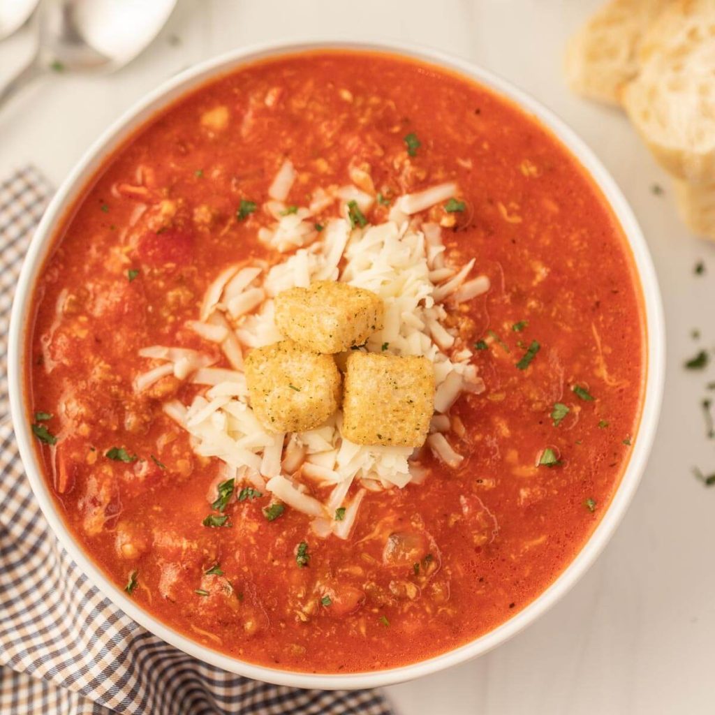 Pizza Soup in a white bowl topped with cheese and croutons