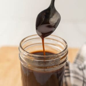 Worcestershire sauce in a jar with a serving on a spoon.