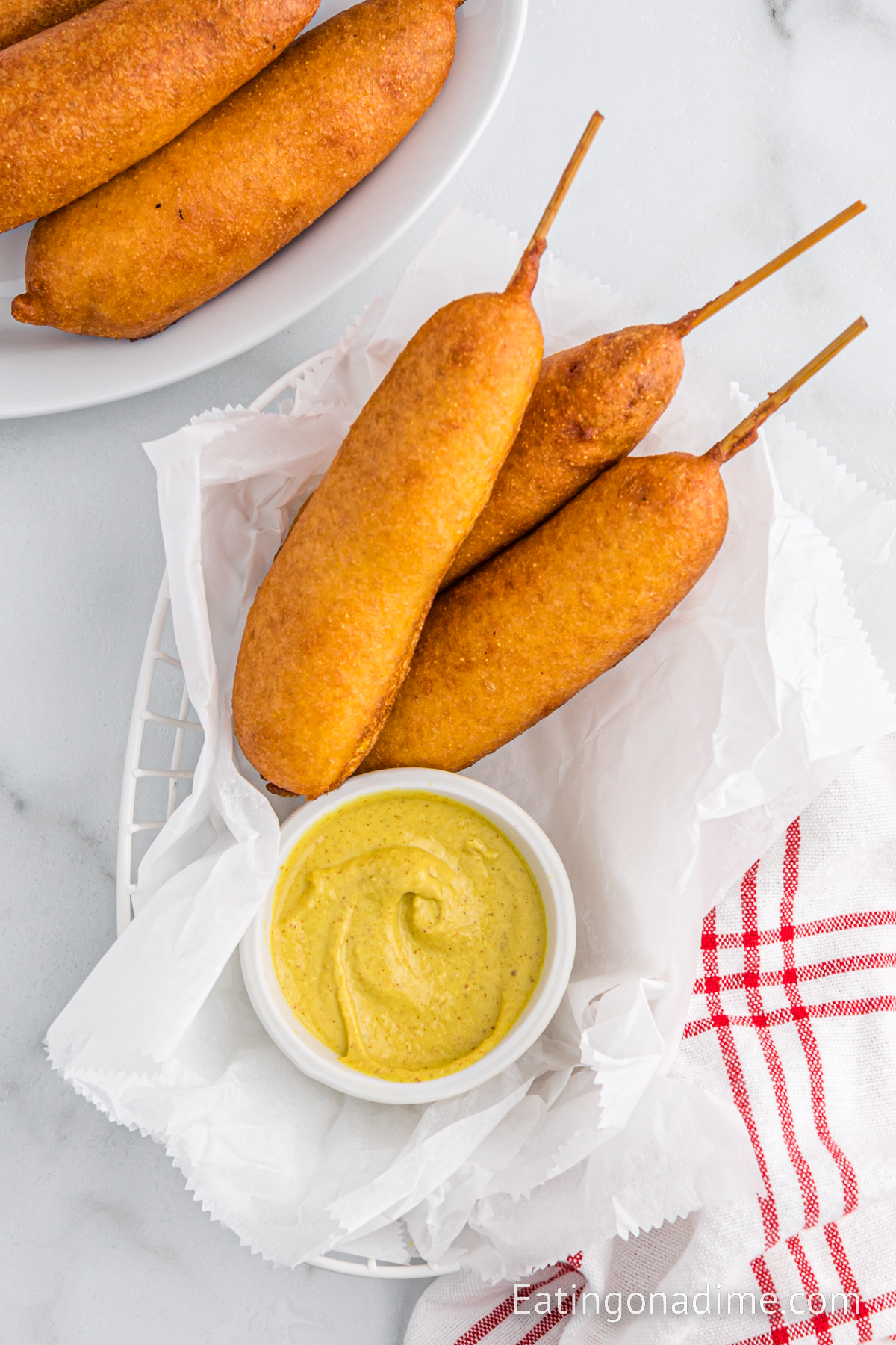 Corndog stacked on a platter with a bowl of mustard