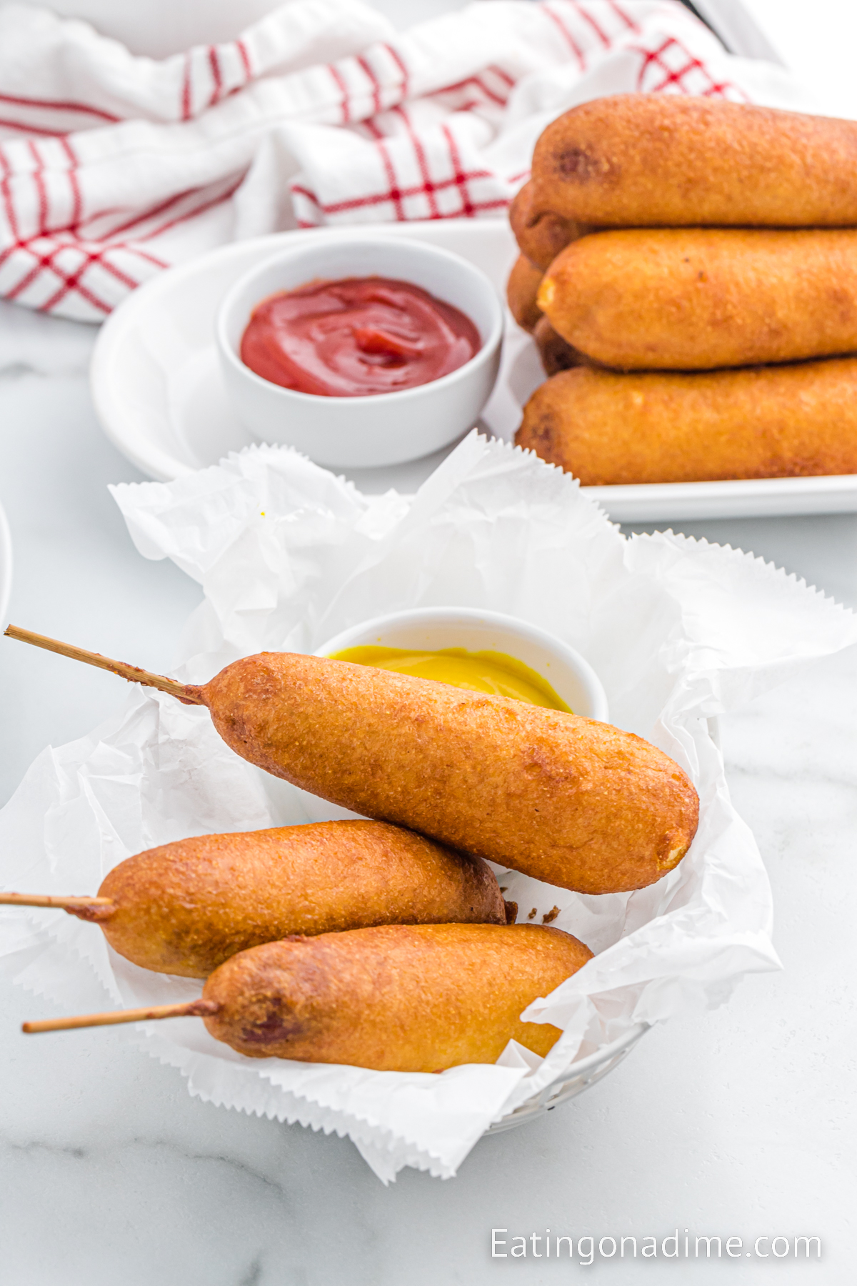 Corndog stacked on a platter with a bowl of mustard