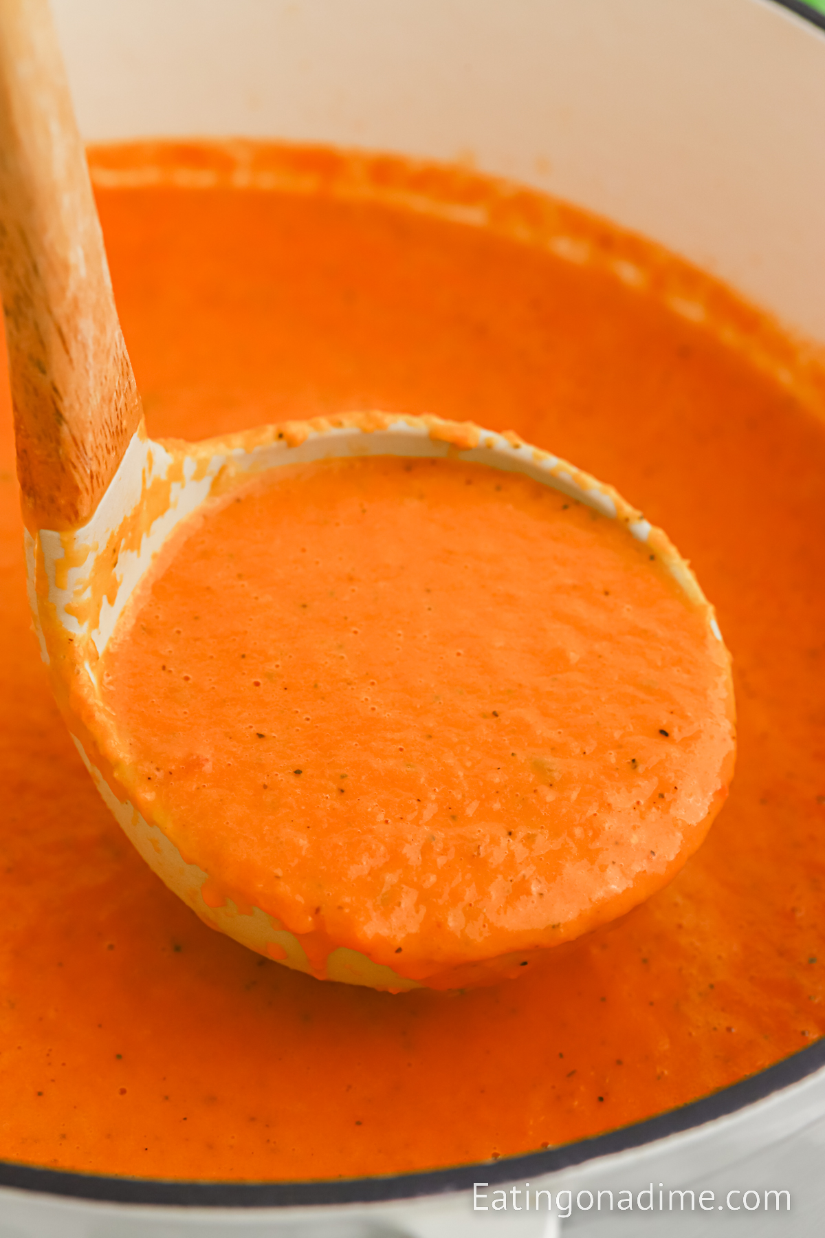 Tomato Soup in a large pot with a serving on a ladle