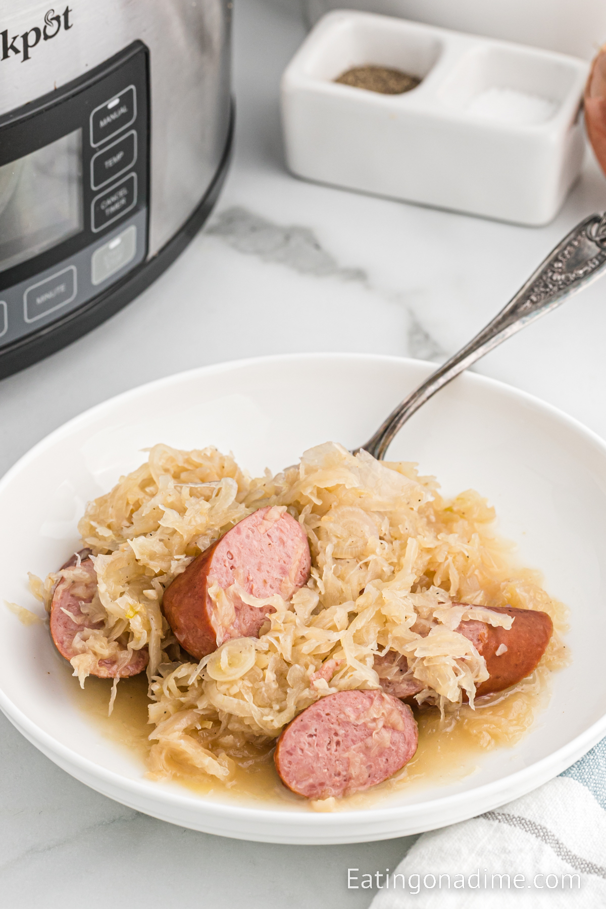 Sauerkraut and slice sausage on a white plate with a fork