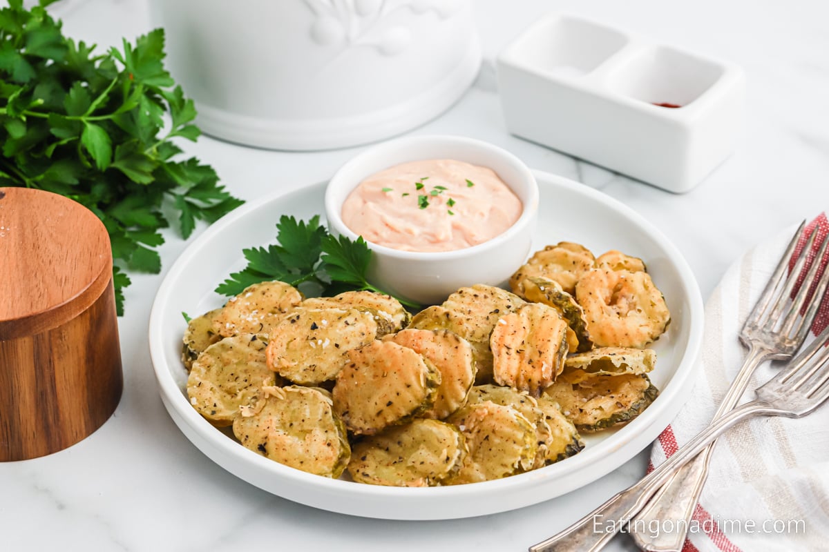 Close up image of fried pickles on a platter with dipping sauce