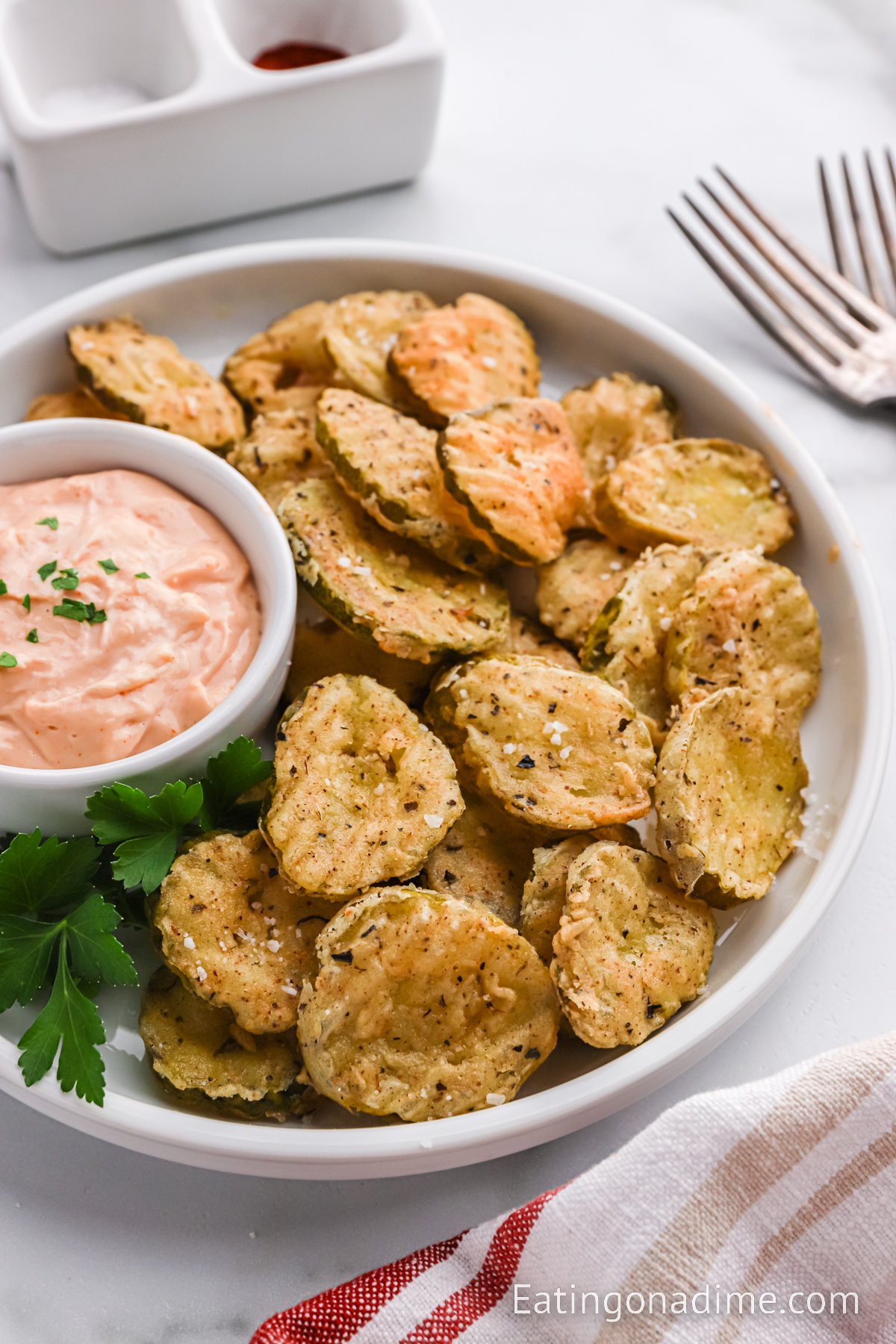 Close up image of fried pickles on a platter with dipping sauce