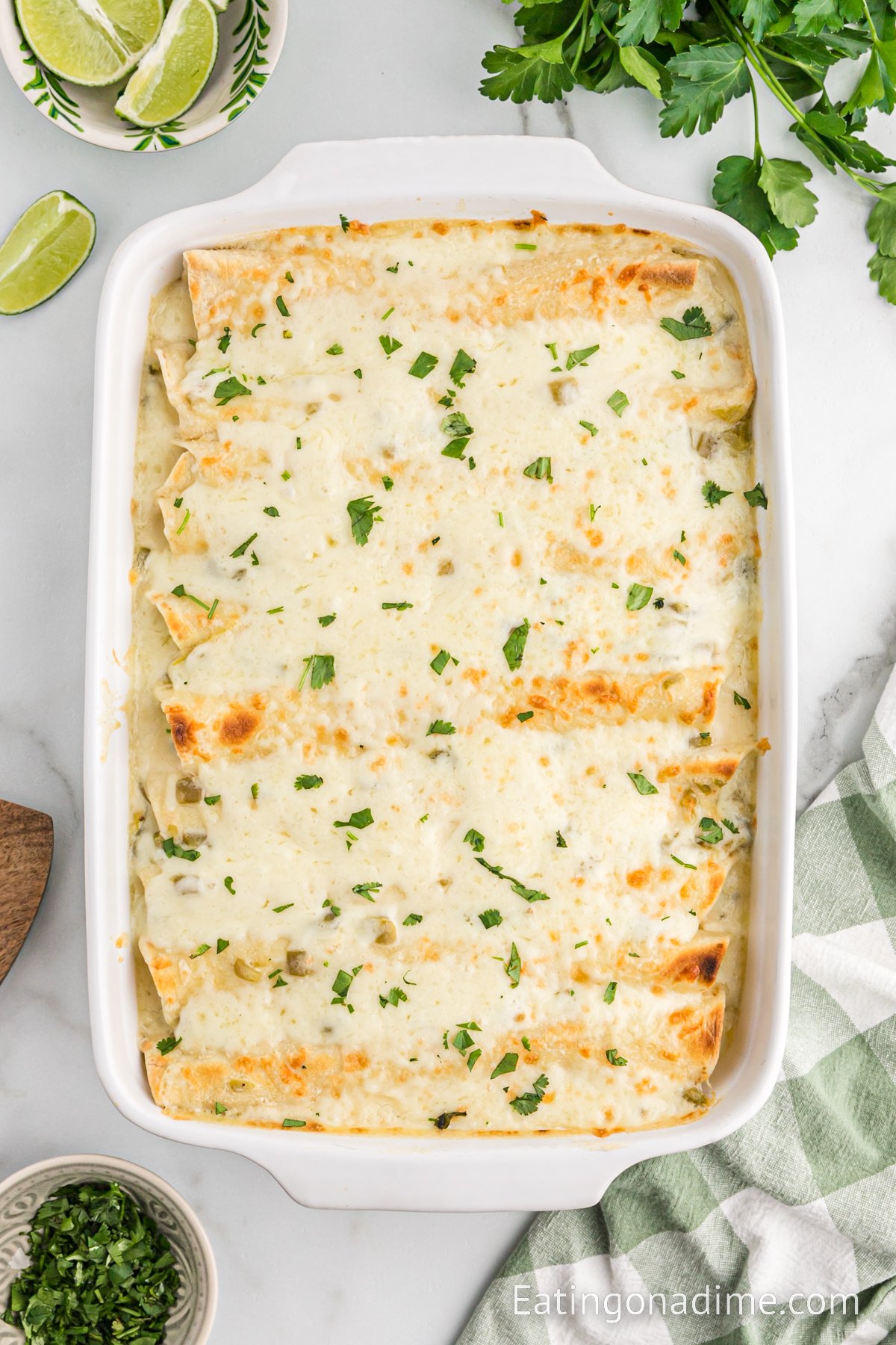White Chicken Enchilada in a casserole dish with a bowl of lime wedges