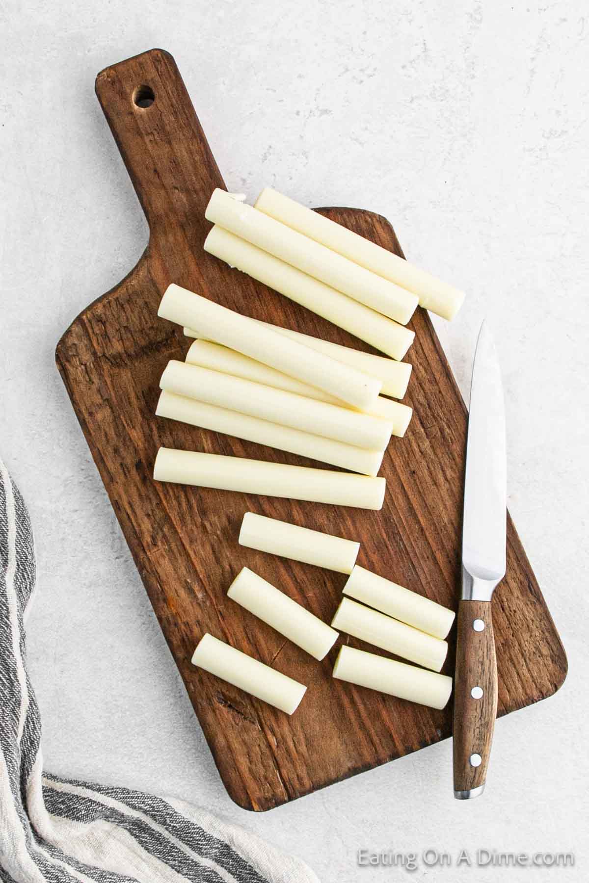 Cutting the cheese sticks in half on a cutting board