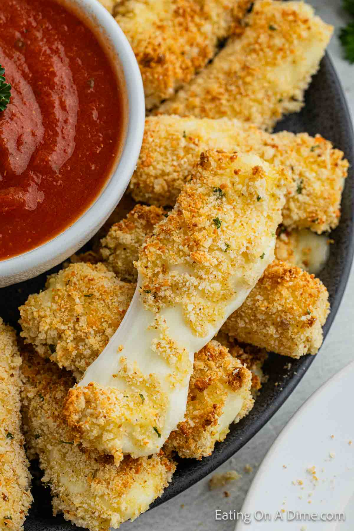 Close up image mozzarella sticks on a platter with a side of pizza sauce