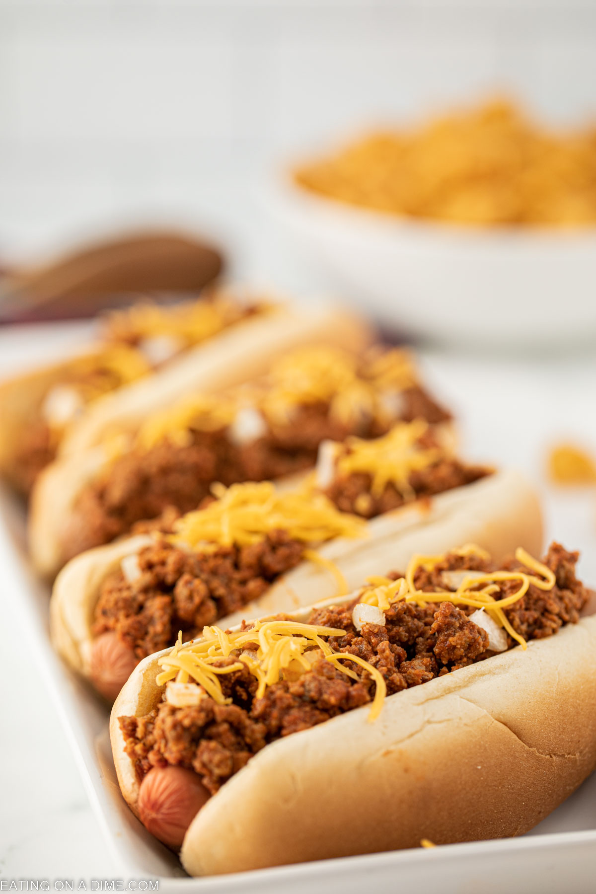 Hot dogs topped with chili, cheese, and onions on a platter