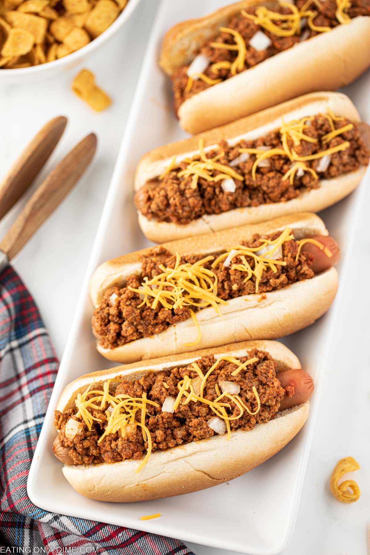 Hot dogs topped with chili, cheese, and onions on a platter