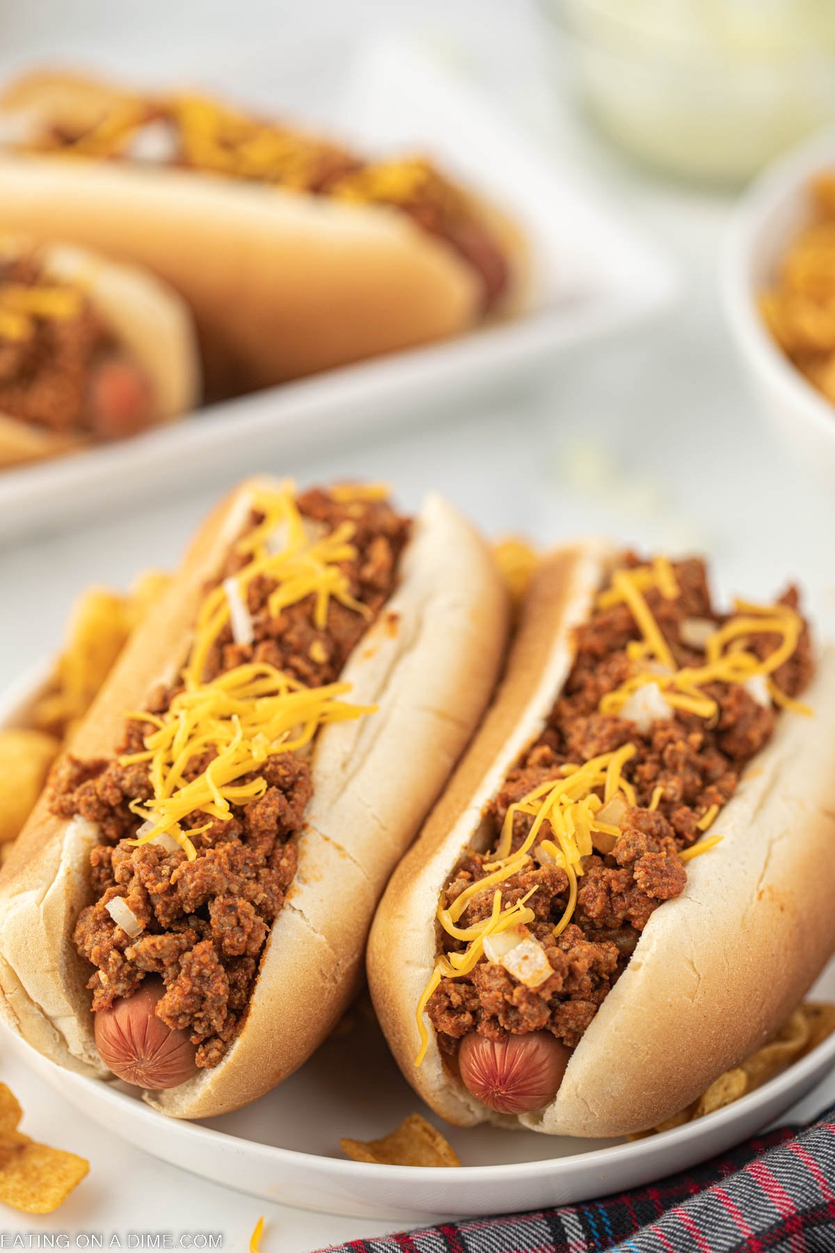 Hot dogs topped with chili, cheese, and onions on a plate