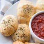 close up of crescent rolls with marinara sauce.