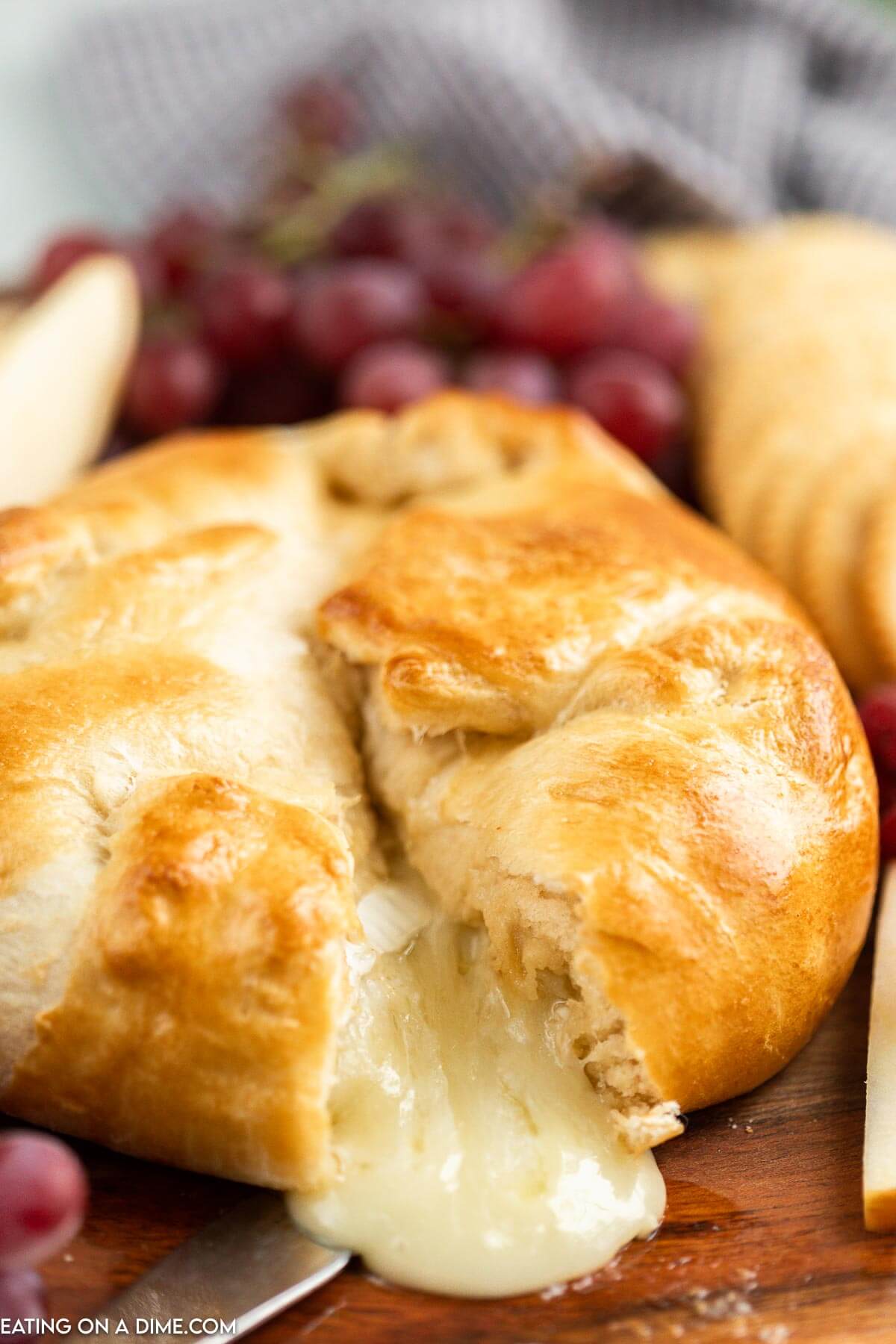 Baked Brie in crescent roll on a platter with a side of fruit and crackers