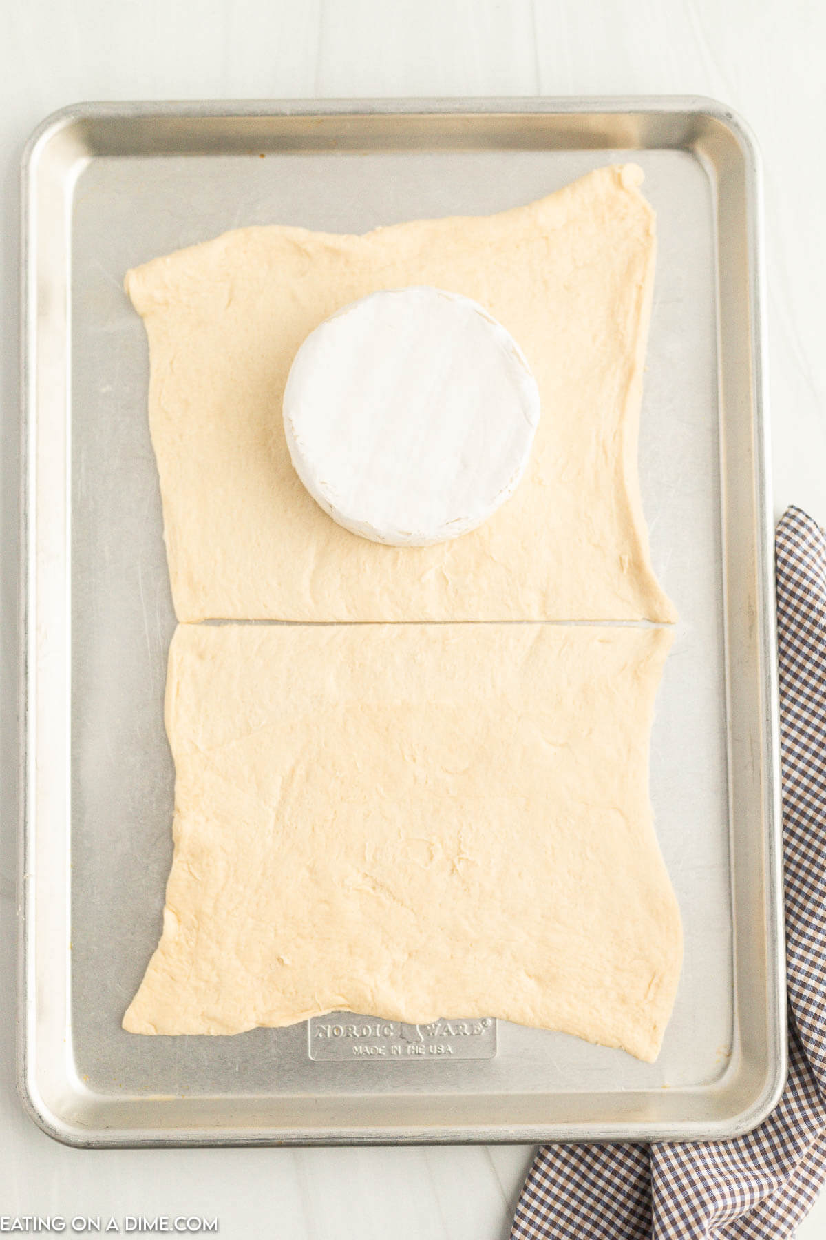 Placing crescent roll on baking sheet with a brie in the center