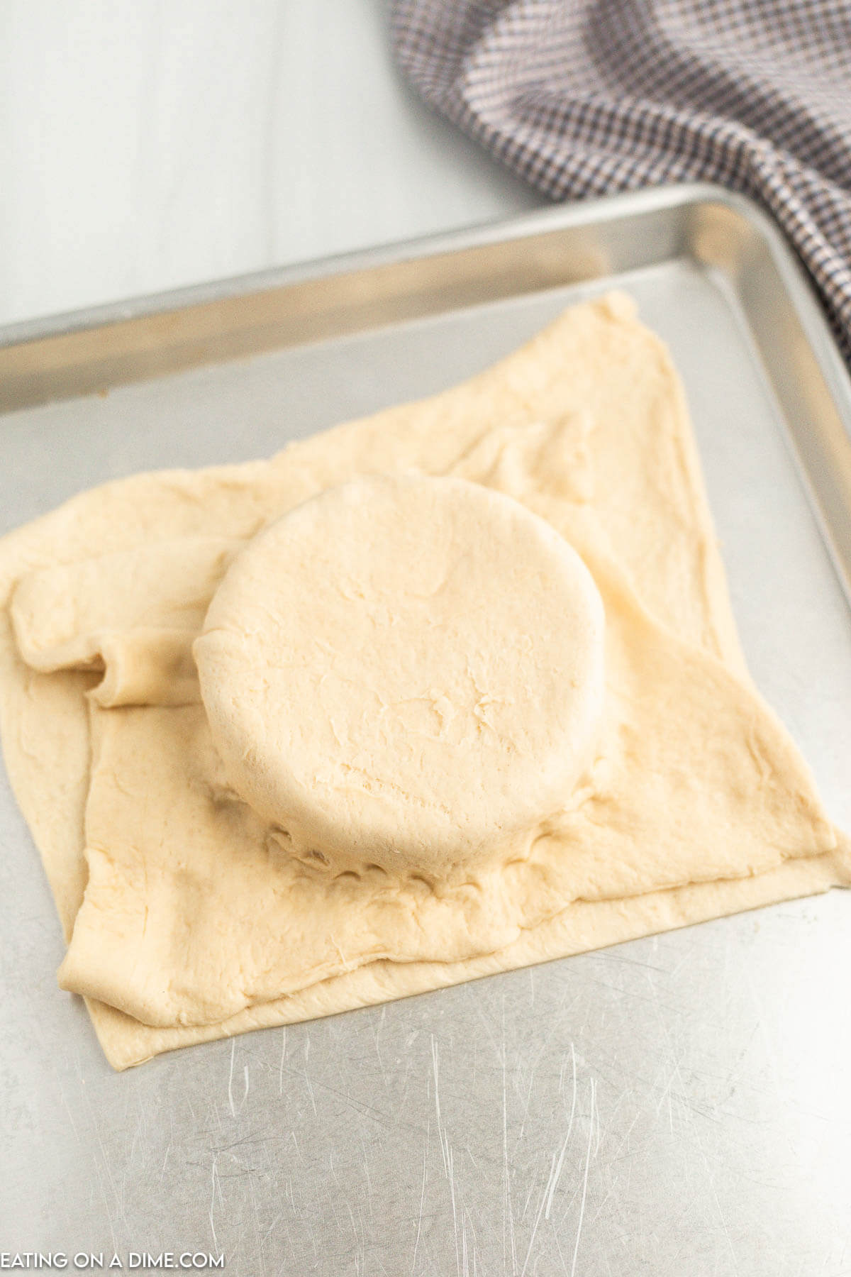 Topping the baked brie with crescent roll