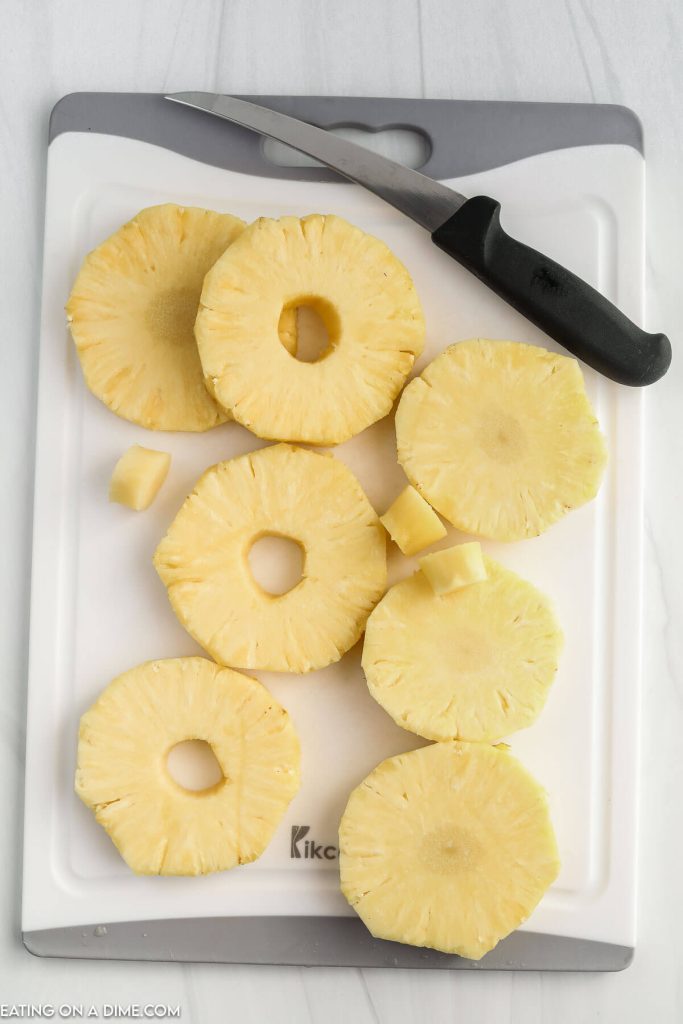 Slicing pineapple on a cutting board with a knife