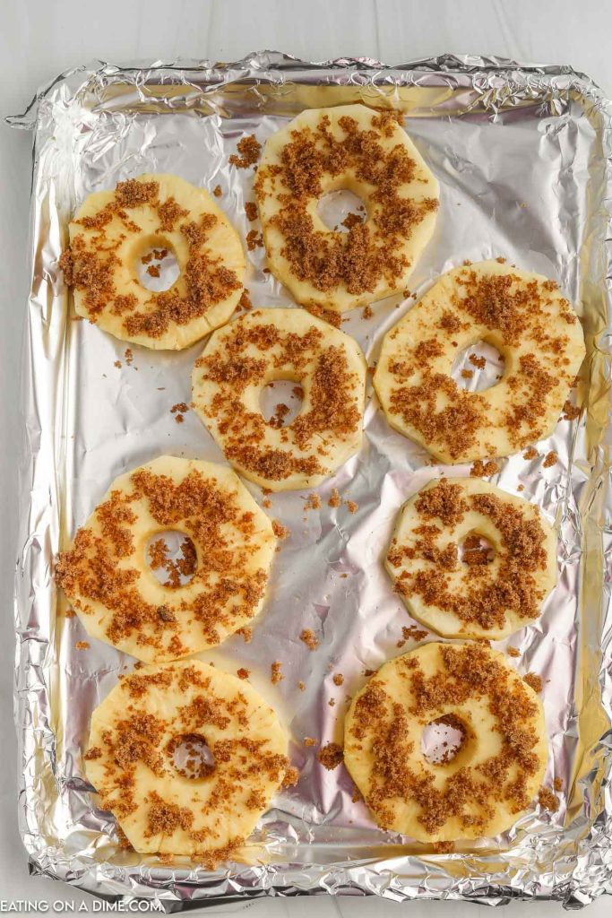 Pineapple slices on a baking sheet sprinkled with brown sugar