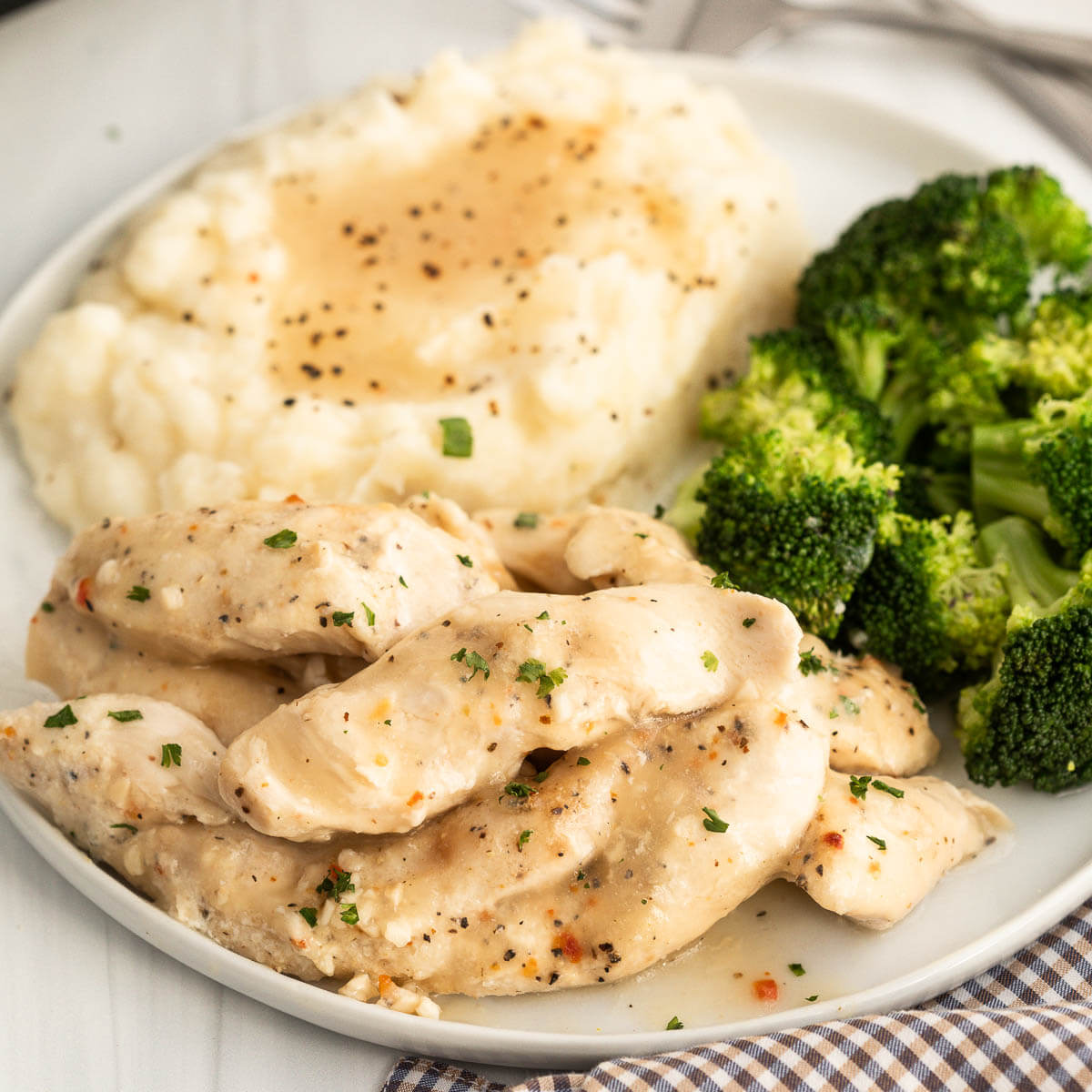 Chicken Tenders on a plate with mashed potatoes and grave with a side of broccoli