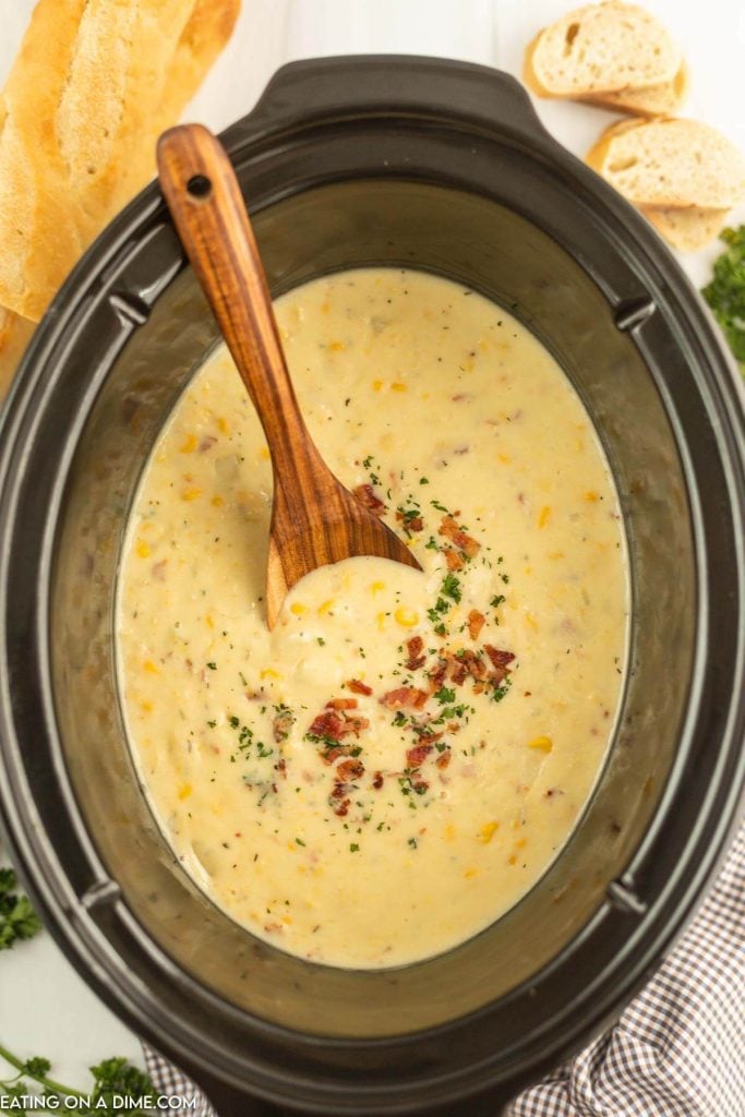Corn chowder in the slow cooker with a wooden spoon