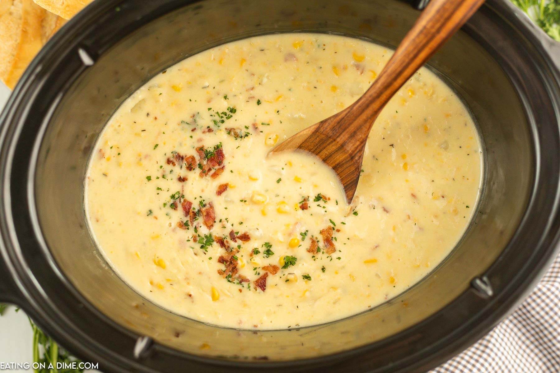 Corn chowder in the slow cooker with a wooden spoon
