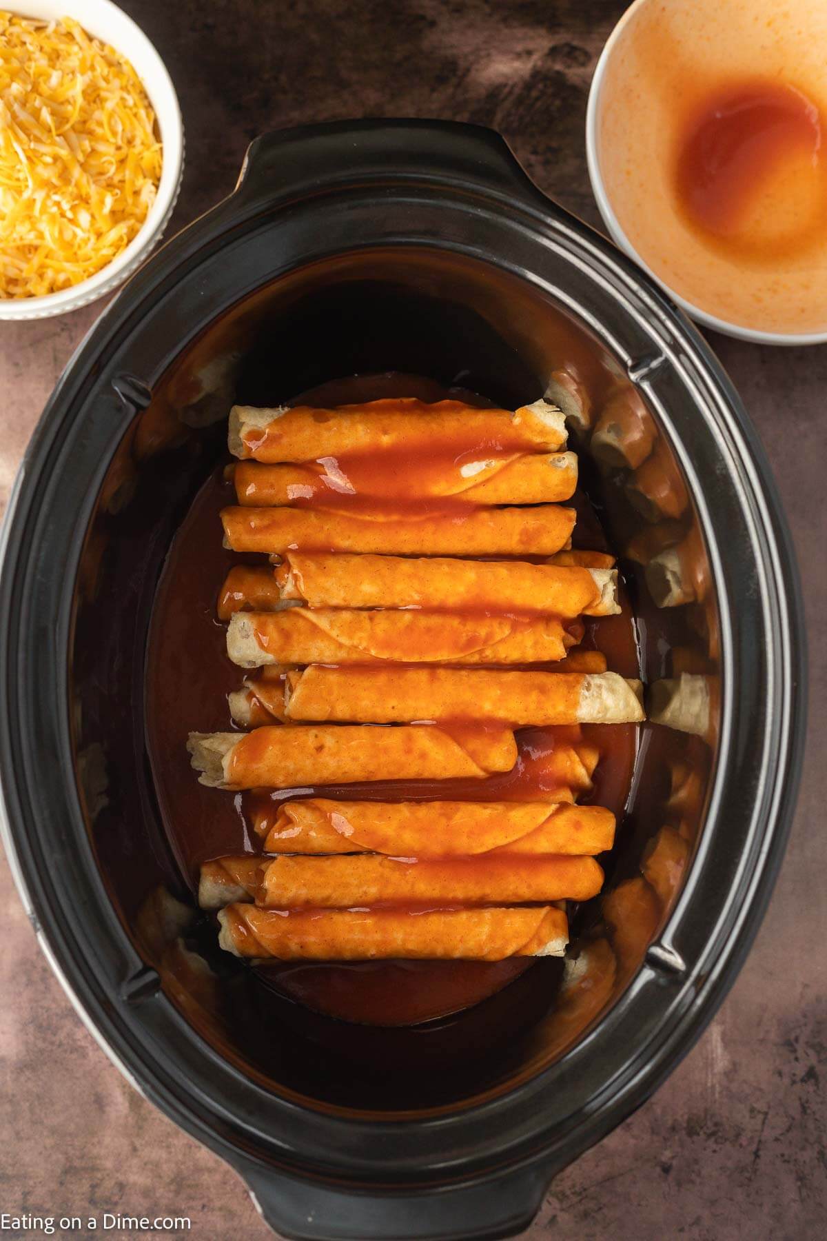 Taquitos in slow cooker topped with enchilada sauce