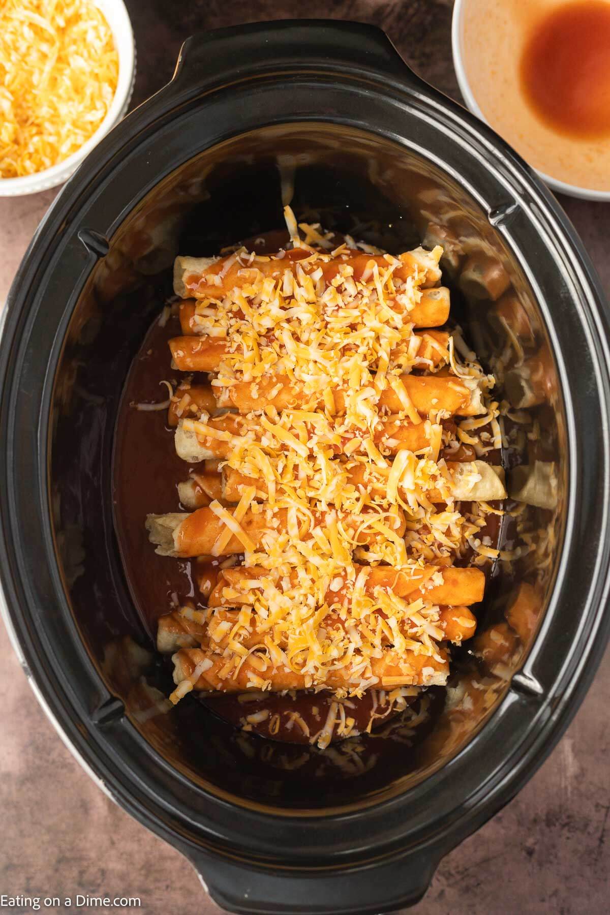 Topping the taquitos with enchilada sauce and cheese