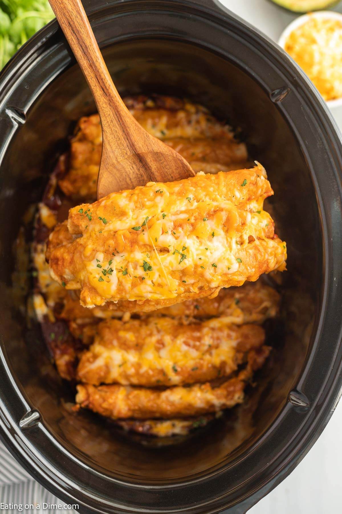 Lazy Enchiladas in a slow cooker with a wooden spoon