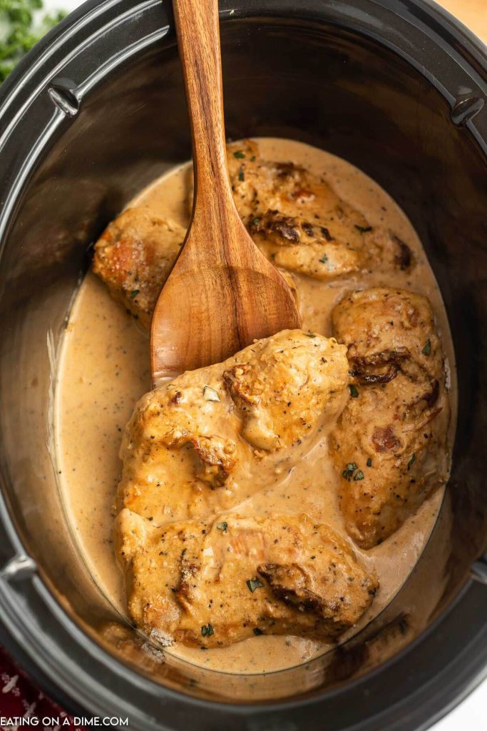Marry Me Chicken in a slow cooker with a wooden spoon