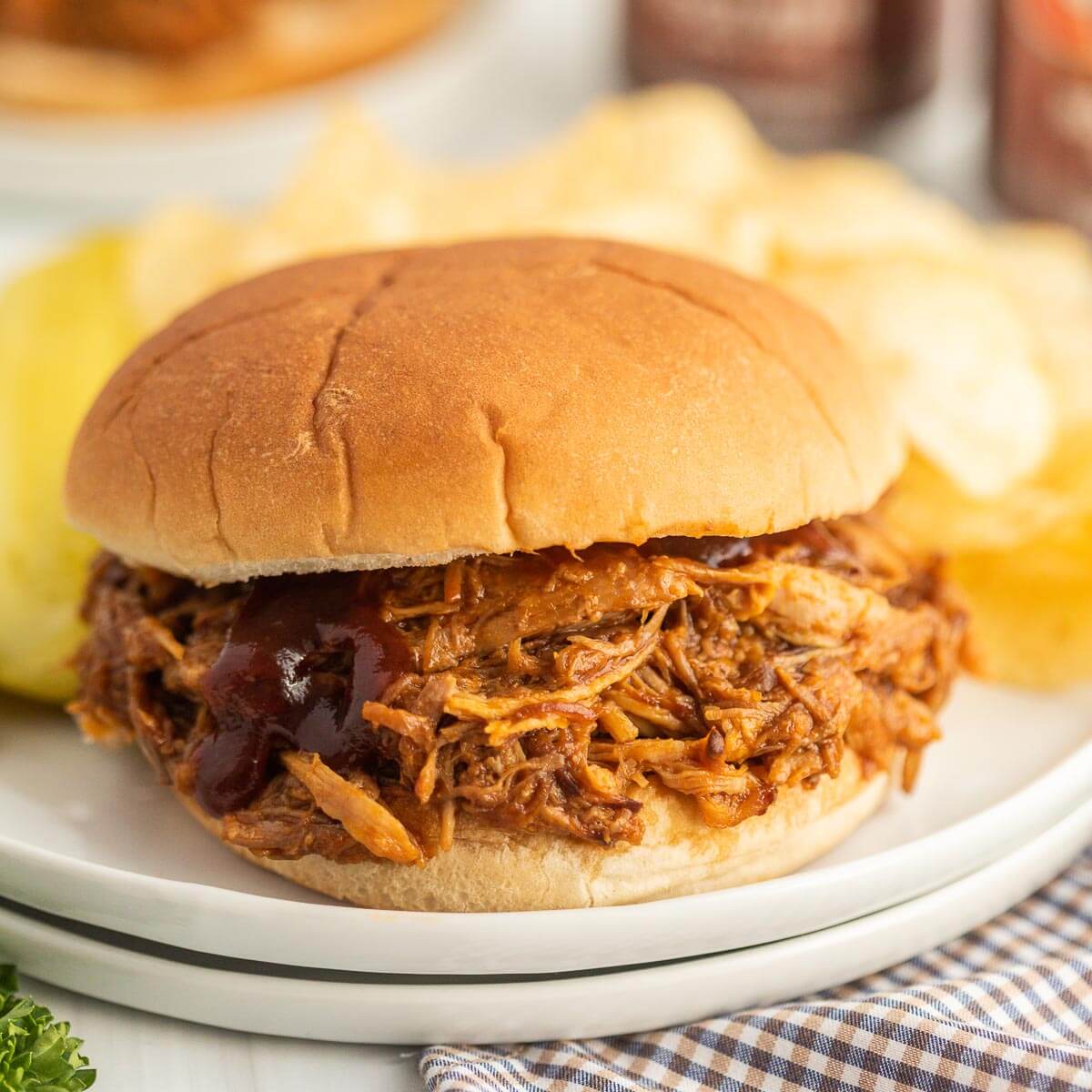 BBQ Pork Sandwich on a plate with chips on the side