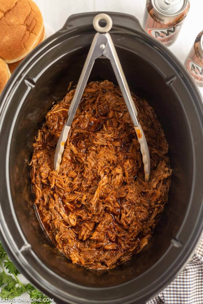 BBQ Shredded pork in the slow cooker with silver tongs