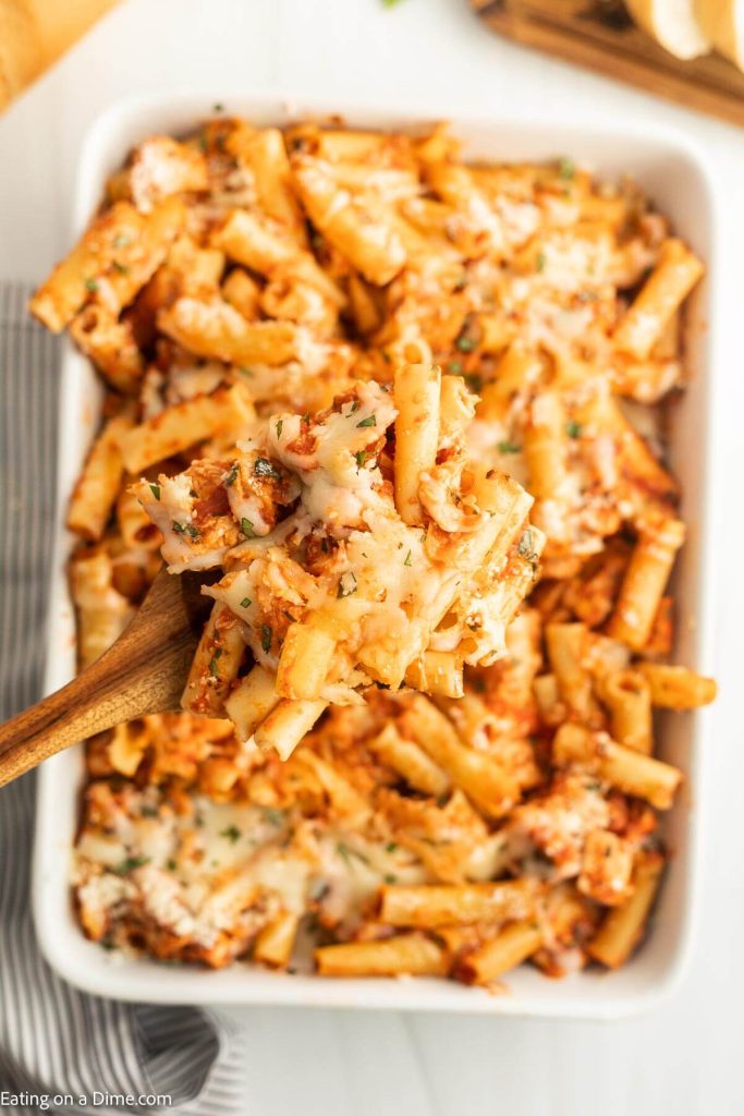 Baked Ziti in a casserole dish with a serving on a wooden spoon