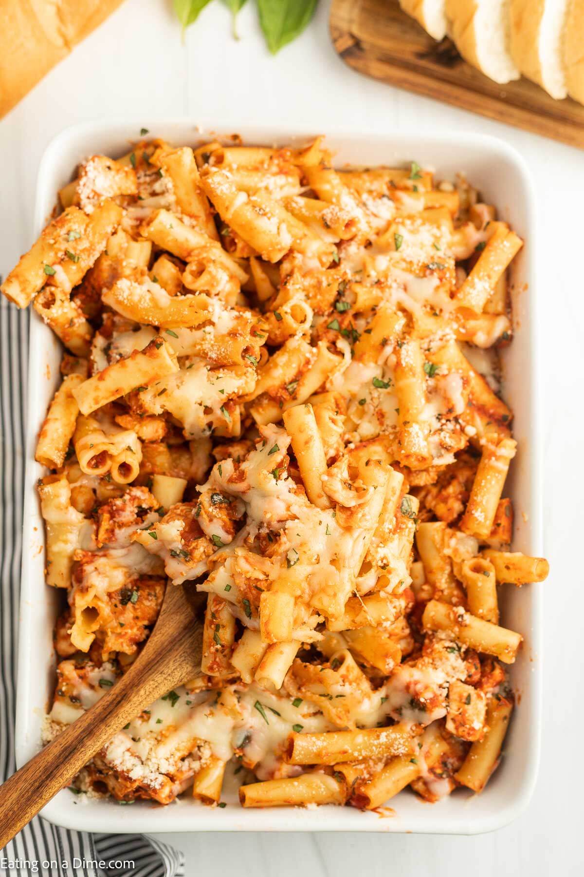 Baked Ziti in a casserole dish with a wooden spoon
