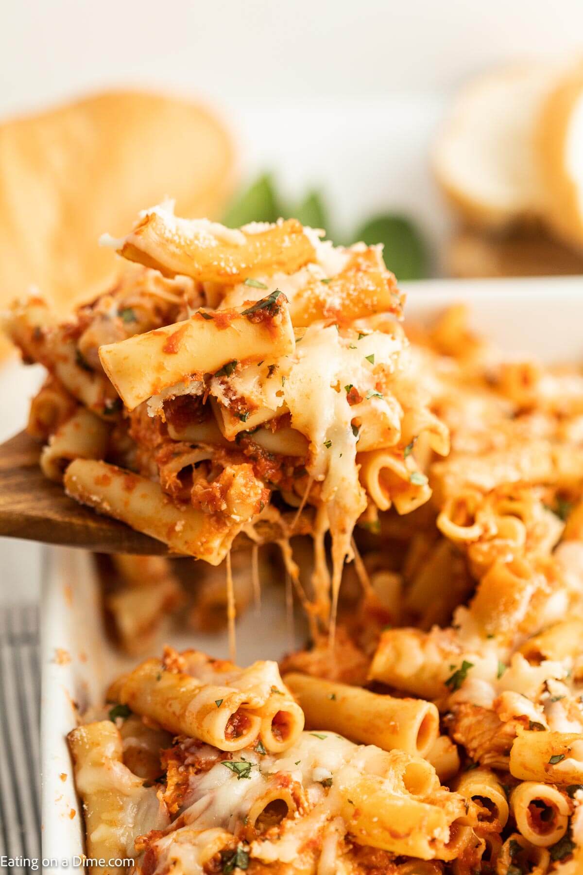 Baked Ziti in a casserole dish with a serving on a wooden spoon