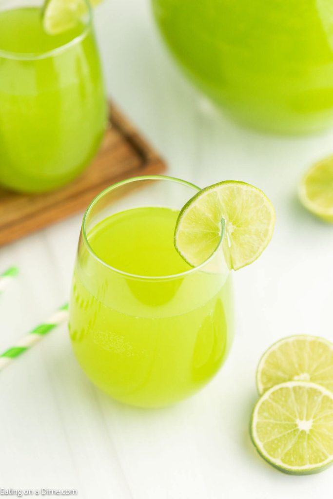 Green Punch in a glass with a lime wedge on the side of the glass