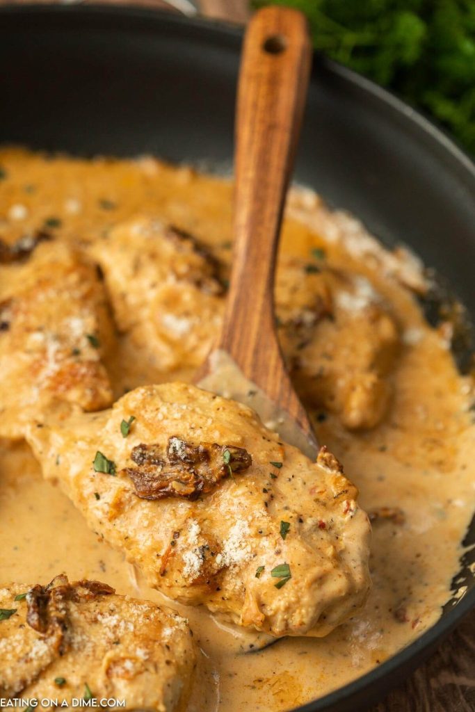 Marry Me Chicken in a skillet with a wooden spoon