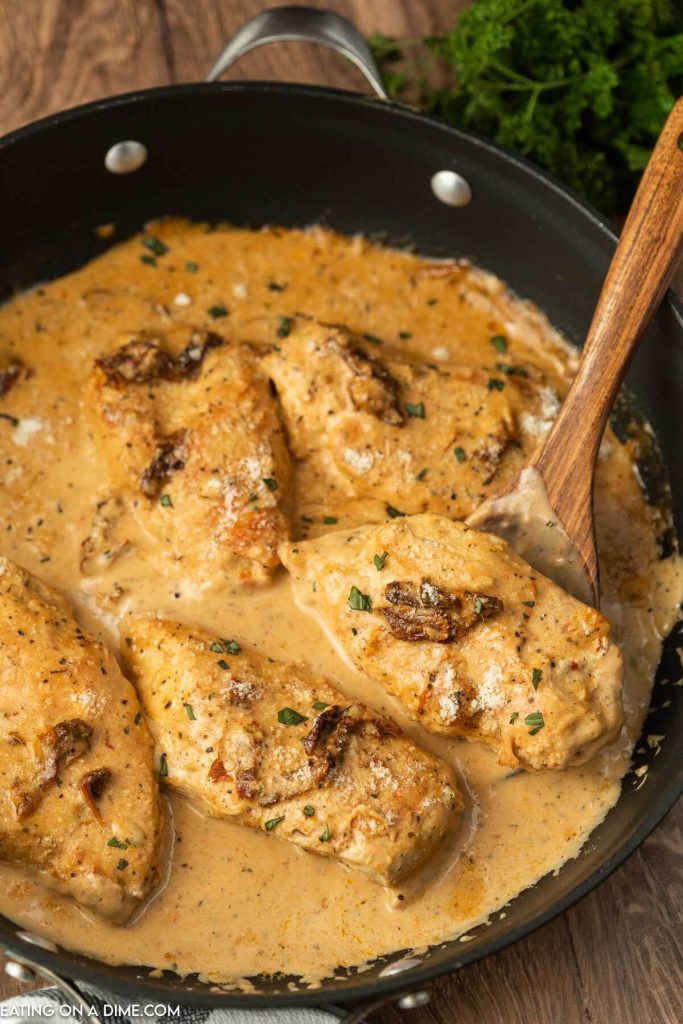 Marry Me Chicken in a skillet with a wooden spoon