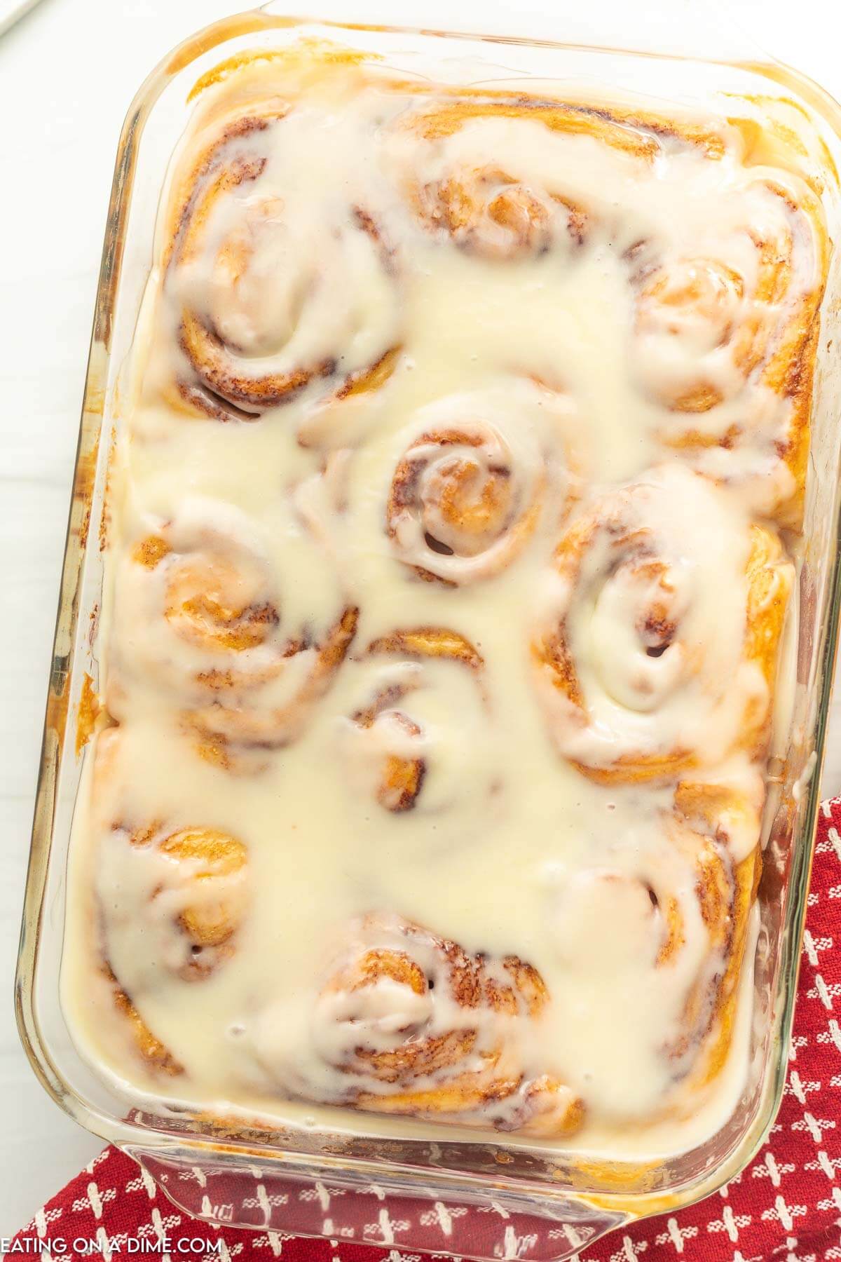 Baked cinnamon rolls in a baking dish covered with icing