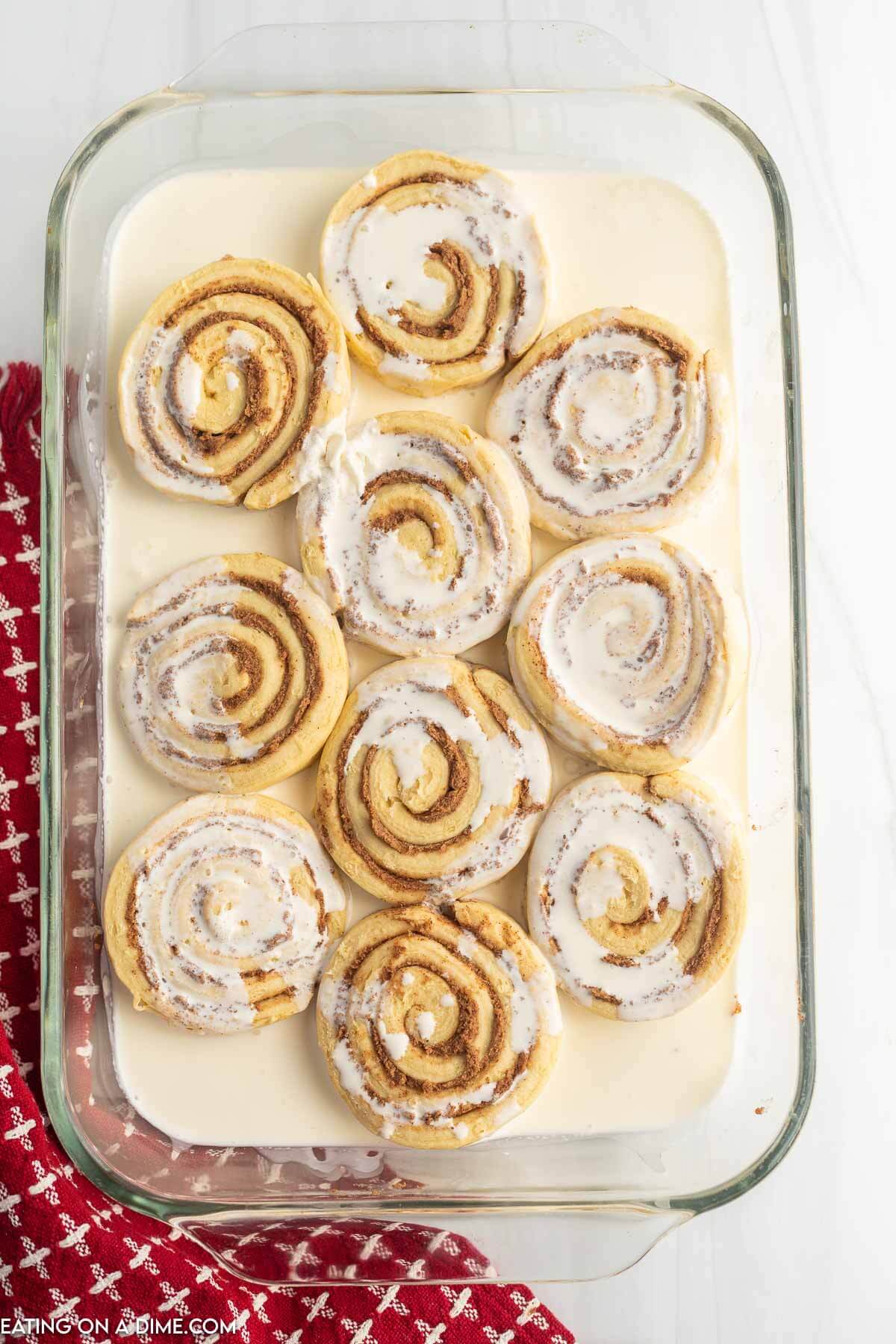 Canned cinnamon rolls in a baking dish covered with heavy cream