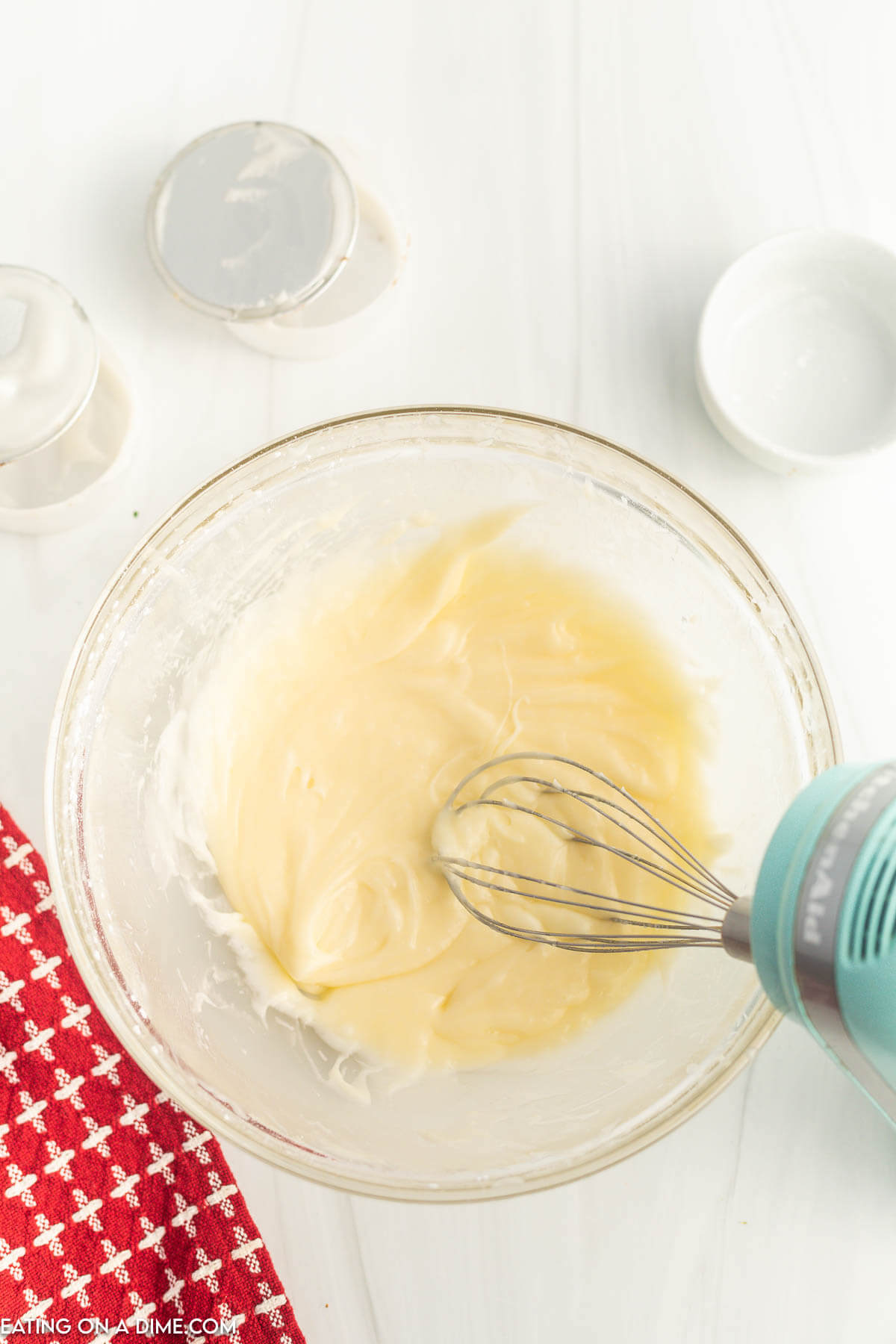 Combining the icing mixture together in a glass bowl with a hand mixer